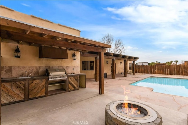 view of swimming pool featuring a patio, a grill, fence, exterior kitchen, and a sink