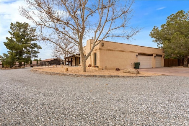 view of front of property with a garage, driveway, fence, and stucco siding