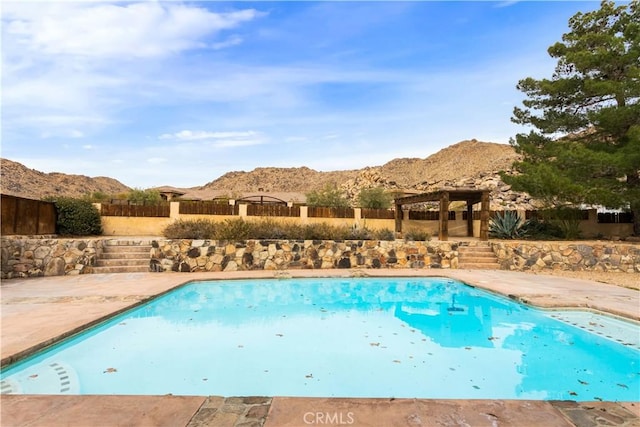 view of swimming pool with a gazebo, a patio, fence, and a mountain view