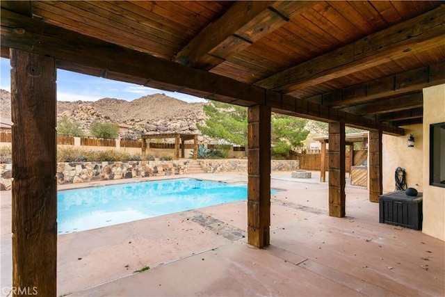 view of pool featuring a patio area, fence, a mountain view, and a fenced in pool