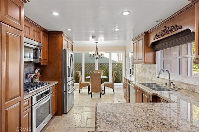 kitchen featuring a sink, light stone counters, stone tile flooring, stainless steel appliances, and a chandelier