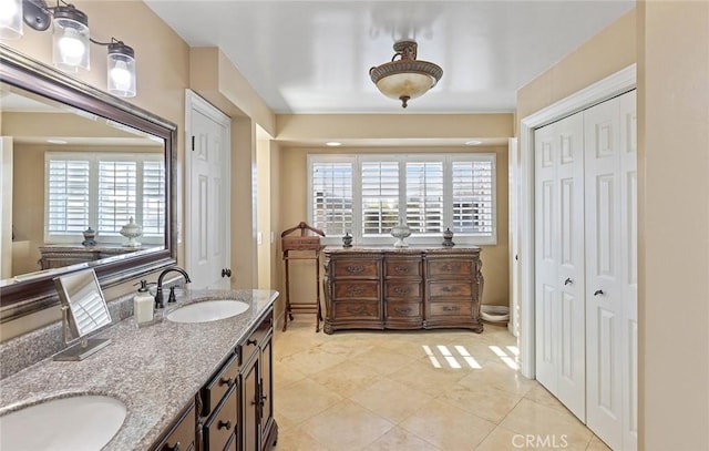 full bath featuring a wealth of natural light, double vanity, a closet, and a sink