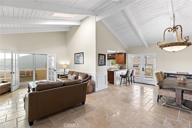 living area with beam ceiling, high vaulted ceiling, french doors, and stone tile flooring