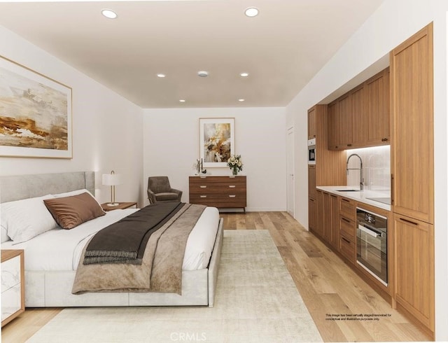 bedroom featuring light wood-style flooring, recessed lighting, and a sink