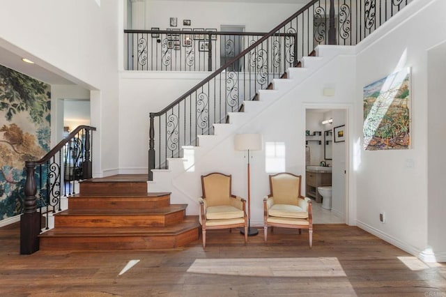 stairs with baseboards, a high ceiling, and wood finished floors