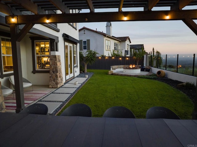 yard at dusk featuring a patio area, fence, and an outdoor fire pit