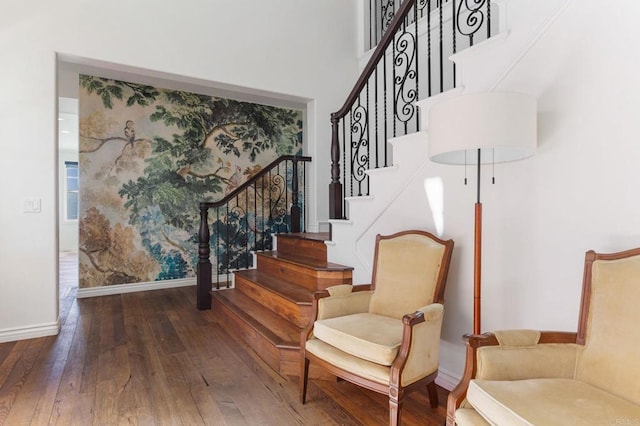 staircase with a towering ceiling, baseboards, and wood-type flooring