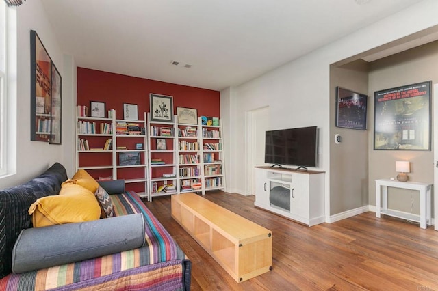 living area featuring visible vents, baseboards, and wood finished floors