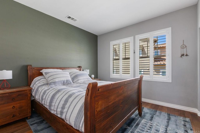 bedroom with wood finished floors, visible vents, and baseboards