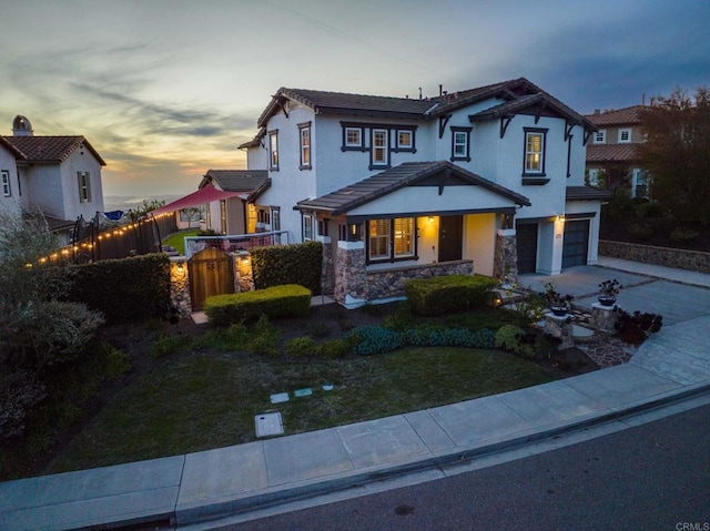 view of front of home featuring a front lawn, driveway, stone siding, fence, and an attached garage