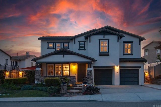 traditional-style home featuring a porch, stucco siding, driveway, and an attached garage