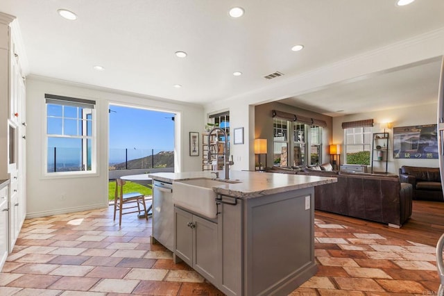 kitchen with visible vents, gray cabinetry, a sink, stainless steel dishwasher, and open floor plan