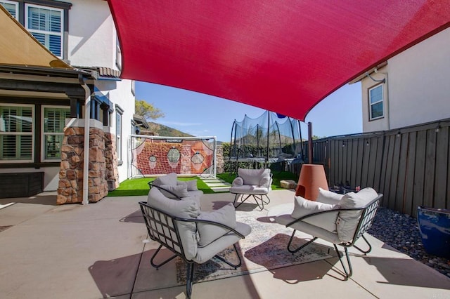 view of patio featuring an outdoor hangout area, a trampoline, and a fenced backyard