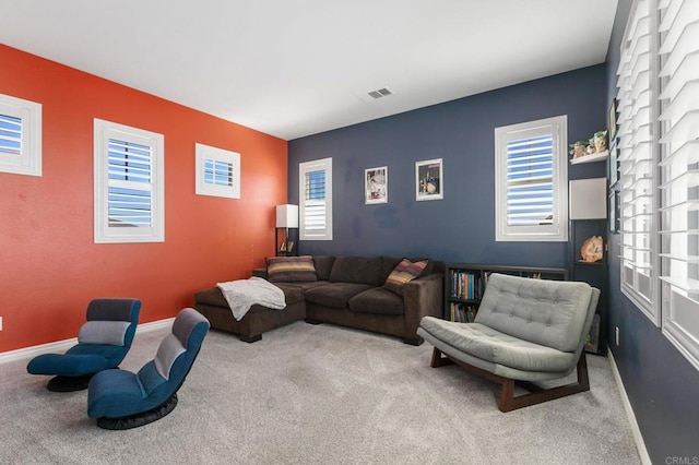 living area with visible vents, an accent wall, baseboards, and carpet floors