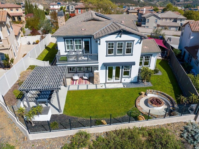 rear view of house with a lawn, a fenced backyard, an outdoor fire pit, french doors, and a patio area