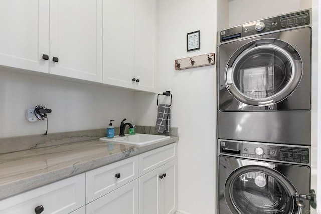 clothes washing area with stacked washer / dryer, cabinet space, and a sink