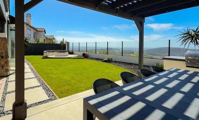 view of yard featuring outdoor dining area, a fenced backyard, a patio area, a mountain view, and a pergola