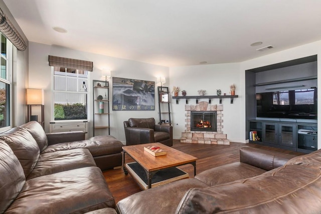 living area with visible vents, a fireplace, baseboards, and wood finished floors