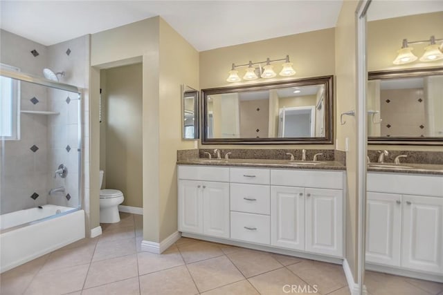 full bath with double vanity, toilet, a sink, tile patterned flooring, and baseboards