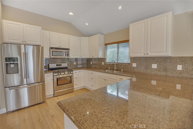 kitchen featuring tasteful backsplash, appliances with stainless steel finishes, light stone counters, vaulted ceiling, and a sink