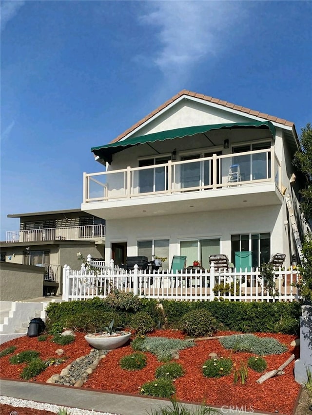 view of front facade with fence, a balcony, and stucco siding