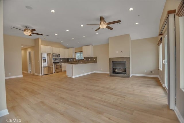 unfurnished living room with lofted ceiling, light wood-style flooring, and ceiling fan