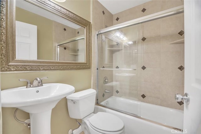 full bath with toilet, bath / shower combo with glass door, and a sink