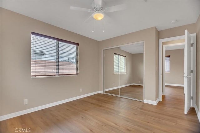 unfurnished bedroom featuring a closet, ceiling fan, light wood-style flooring, and baseboards