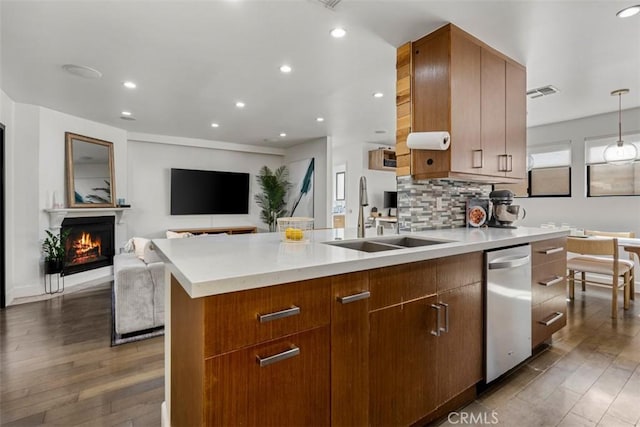 kitchen with a warm lit fireplace, a sink, visible vents, light countertops, and decorative backsplash