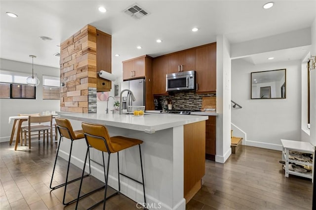 kitchen with tasteful backsplash, visible vents, appliances with stainless steel finishes, a breakfast bar area, and light countertops