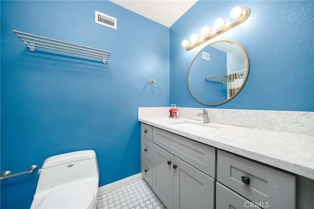 bathroom featuring tile patterned flooring, toilet, vanity, visible vents, and baseboards