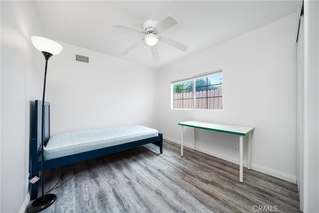 bedroom featuring a ceiling fan, visible vents, baseboards, and wood finished floors