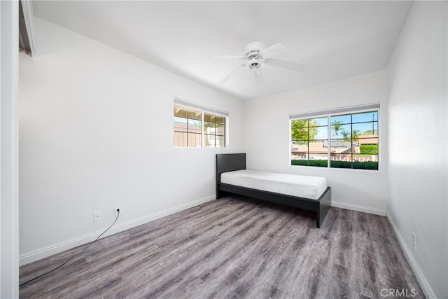 unfurnished bedroom with a ceiling fan, baseboards, and wood finished floors