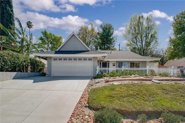 ranch-style home with driveway, an attached garage, fence, and stucco siding