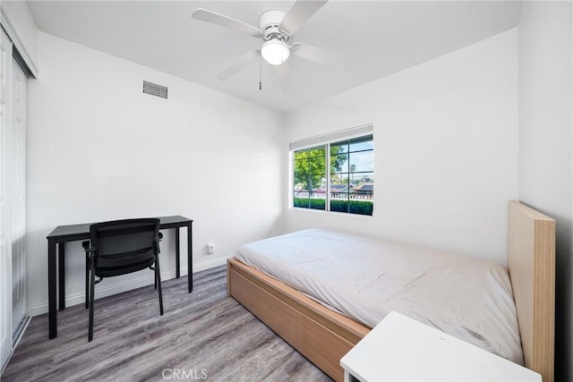 bedroom featuring a closet, visible vents, a ceiling fan, wood finished floors, and baseboards