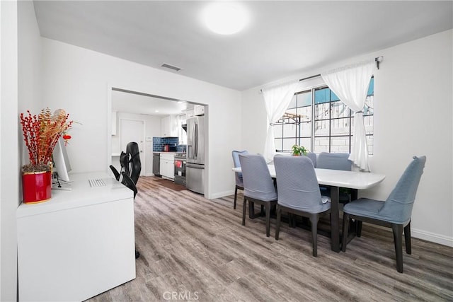 dining area featuring wood finished floors, visible vents, and baseboards