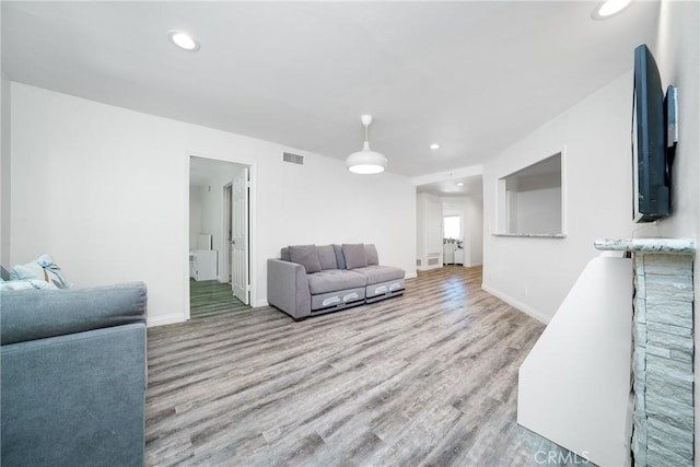 living room with recessed lighting, visible vents, baseboards, and wood finished floors