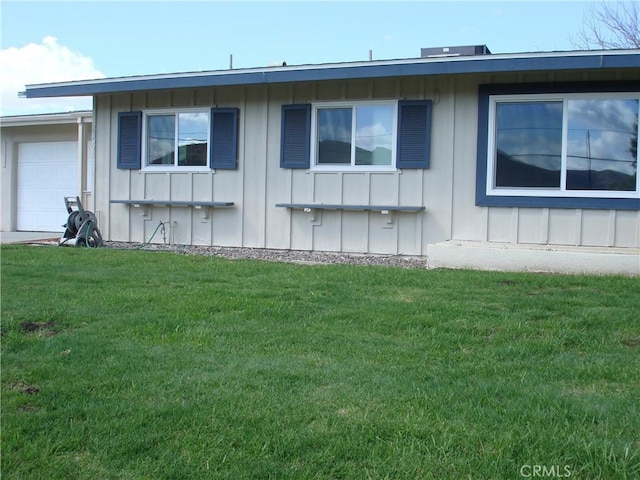 view of side of home with board and batten siding, a yard, and an attached garage