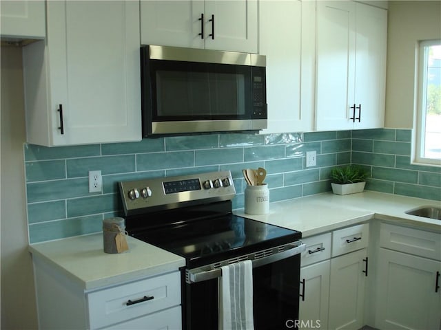 kitchen featuring white cabinetry, appliances with stainless steel finishes, decorative backsplash, and light countertops