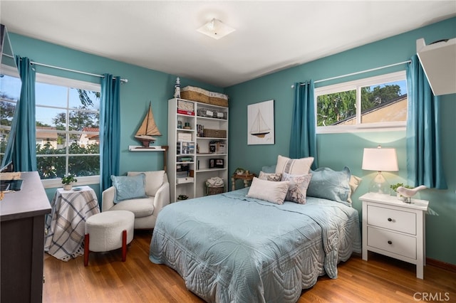 bedroom with multiple windows and wood finished floors