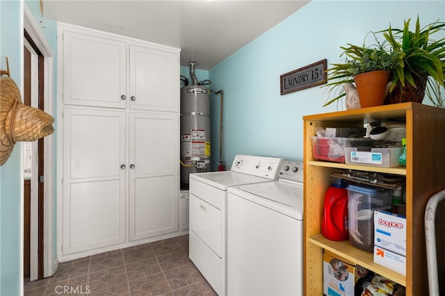 laundry area with dark tile patterned flooring, water heater, cabinet space, and separate washer and dryer