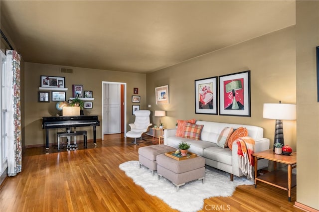 living area featuring wood finished floors, visible vents, and baseboards