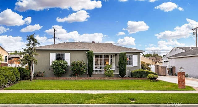 view of front of house featuring a front yard, a gate, fence, and stucco siding