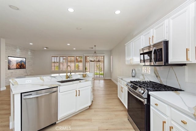 kitchen featuring light stone counters, appliances with stainless steel finishes, white cabinetry, a sink, and light wood-type flooring