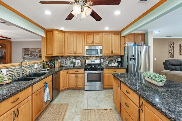 kitchen featuring dark stone countertops, a sink, decorative backsplash, appliances with stainless steel finishes, and crown molding