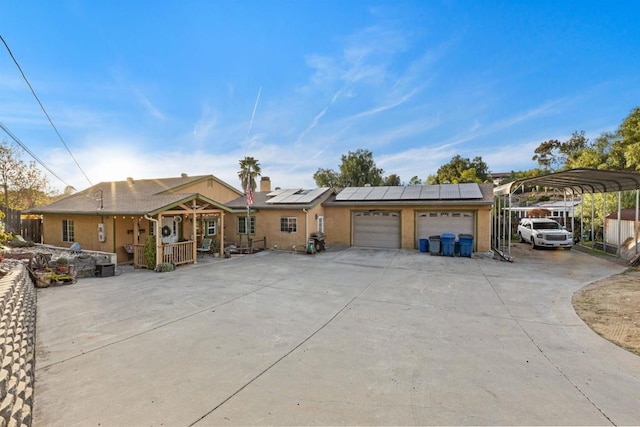 single story home featuring roof mounted solar panels, stucco siding, an attached garage, and concrete driveway