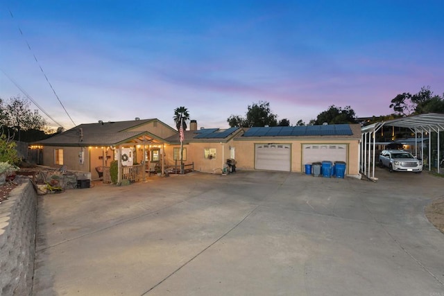 single story home with solar panels, driveway, and a garage