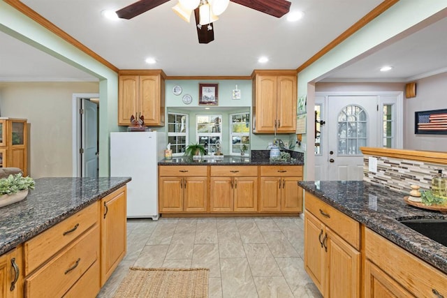 kitchen with dark stone counters, recessed lighting, freestanding refrigerator, decorative backsplash, and crown molding