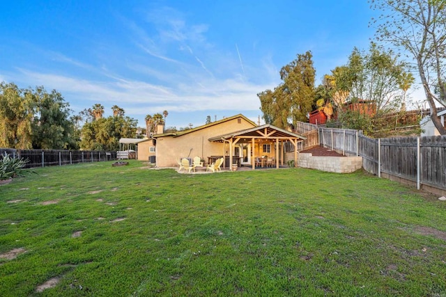 rear view of house with a patio area, a yard, a fenced backyard, and stucco siding