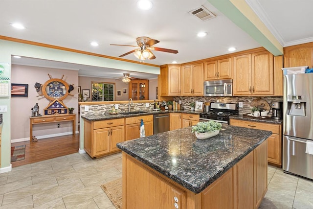 kitchen featuring visible vents, a peninsula, a sink, appliances with stainless steel finishes, and crown molding